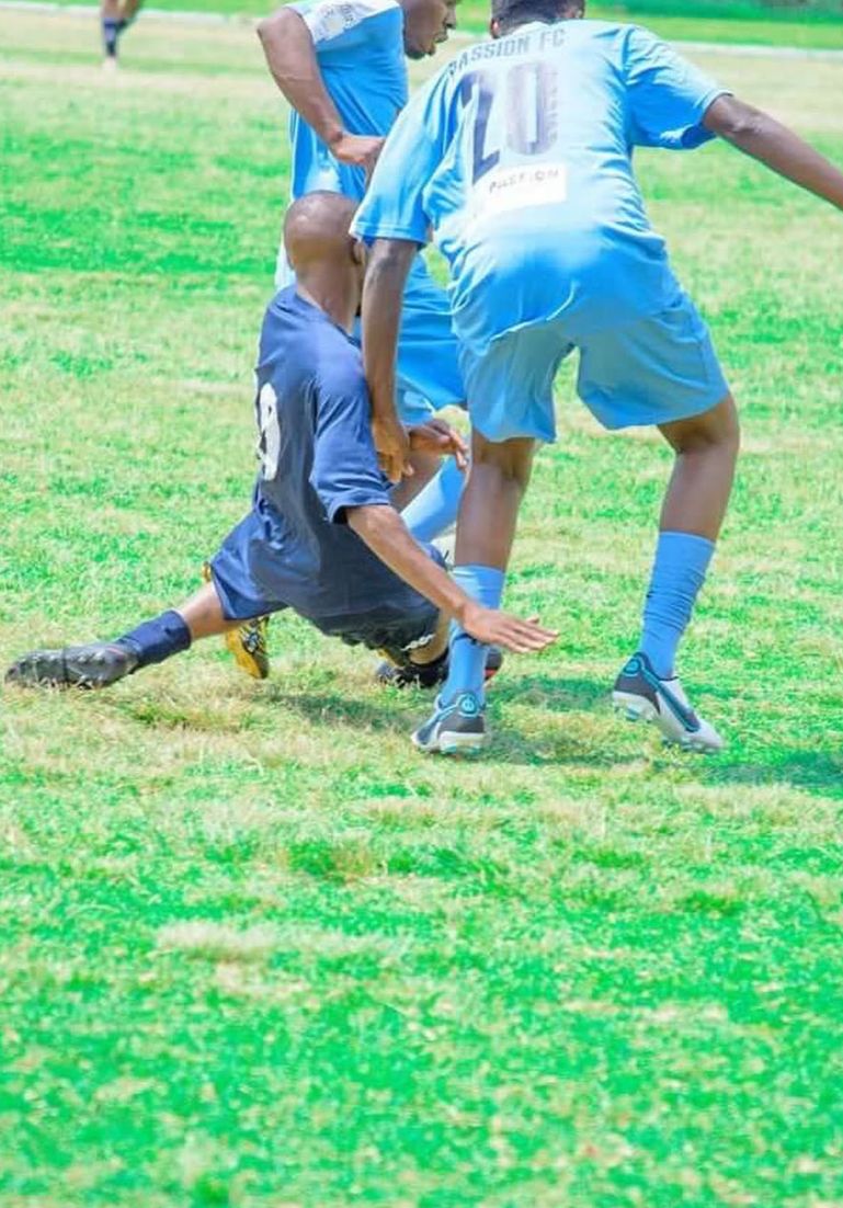 Football players contesting the ball on a grass pitch during a match